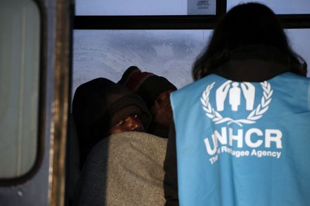 A Congolese refugee looks on as a UNHCR volunteer checks
