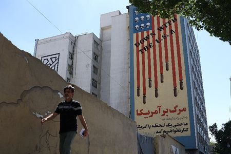 A man walks past an anti-U.S. mural on a building