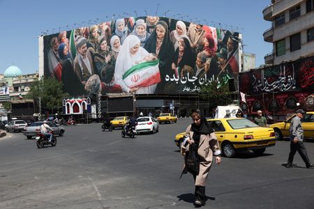 People walk past a billboard with a picture of Iranian
