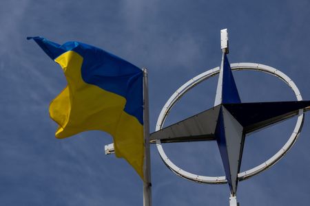 Ukrainian national flag rises in front of the NATO emblem