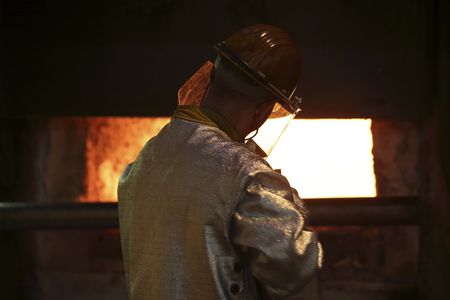 A worker cleans impurities from an aluminium furnace at the