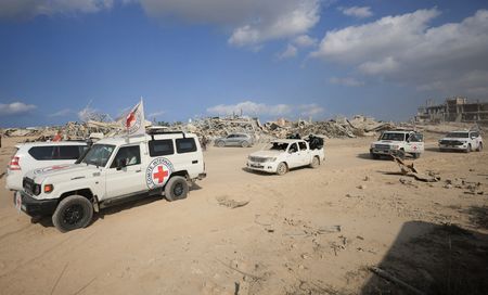 Red Cross personnel, escorted by Hamas militants, wait to head