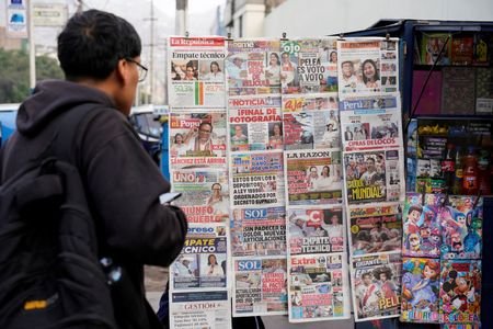 A man looks at a newspaper stand with headlines showing
