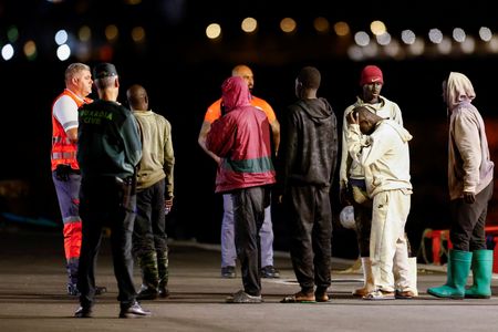 Migrants wait to be attended to after disembarking from a