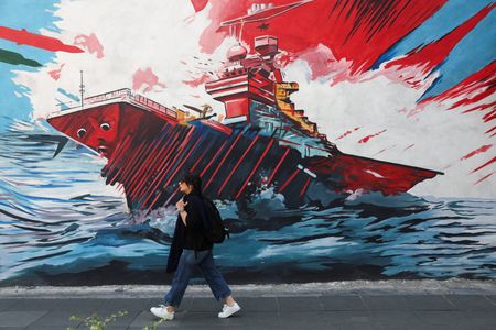 An Iranian woman walks next to an anti-U.S mural on