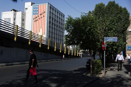 A man walks near an anti-U.S. mural on a building