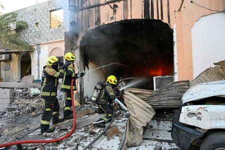 Firefighters work in the aftermath of Iranian drone attacks, at