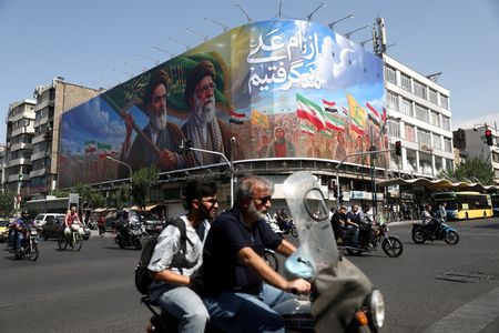 People ride past a billboard depicting the late leader of