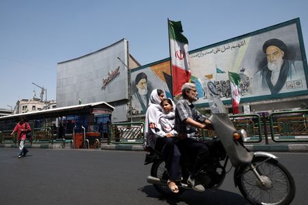People ride past a mural depicting the late leader of