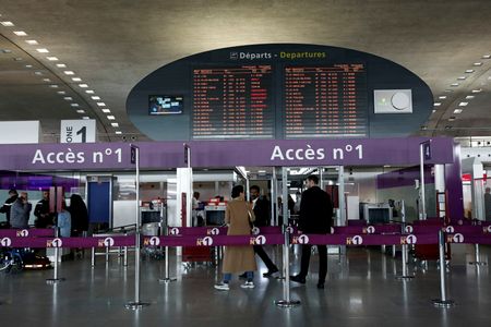 FILE PHOTO: Passengers gather in a departure hall as screens