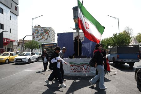 A woman holds an Iranian flag on a street in