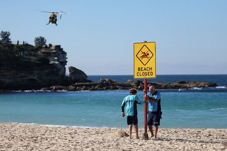 FILE PHOTO: Lifeguards erect a sign that says “Beach Closed”