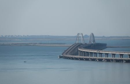 A boat sails next to the Crimean bridge connecting the Russian