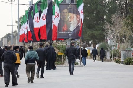FILE PHOTO: People walk along a street with Iranian flags