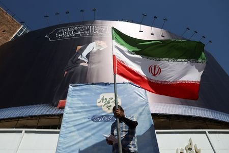 A man holds an Iranian flag on a street, in