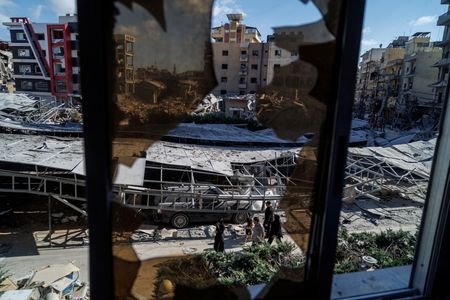 People walk past rubble at the site of an Israeli