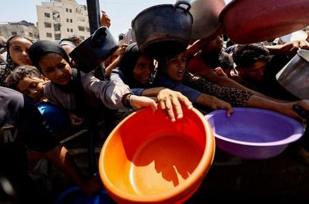 FILE PHOTO: Palestinians wait to receive food from a charity
