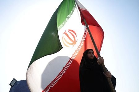 A woman holds an Iranian flag on a street in