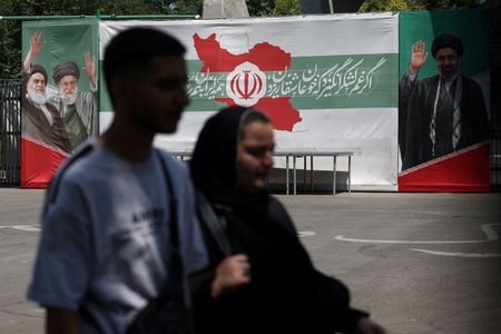 FILE PHOTO: People walk past a banner with pictures of