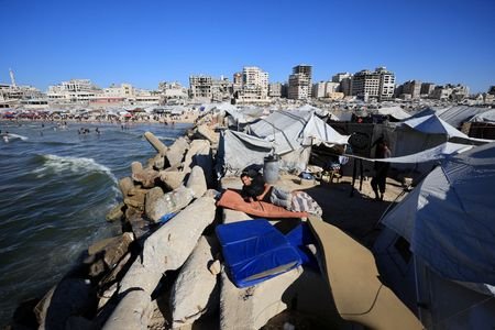 Shihab al-Suwaireki, a displaced Palestinian, rests on a mattress outside