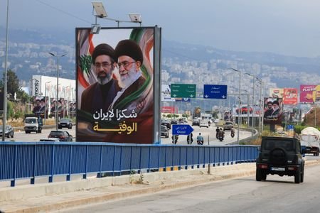 Cars and motorbikes drive past billboards showing Iran’s new Supreme