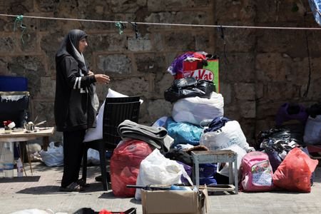 A woman stands near her belongings on a sidewalk in