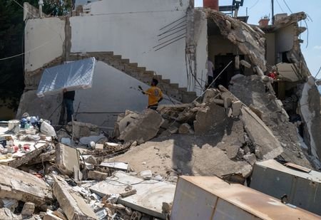 A displaced Lebanese man who survived an Israeli airstrike carries