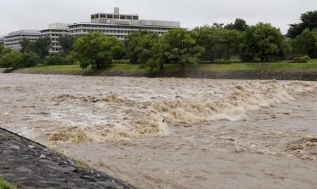 The Kamo River, swollen by heavy rain, flows rapidly in