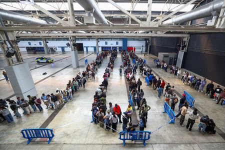 FILE PHOTO: People queue to receive documentation as Spain's mass