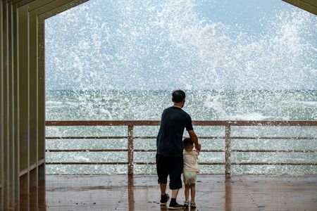 People watch waves crashing against the shore as Tropical Storm