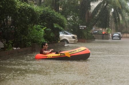 A man rows an inflatable raft inside a waterlogged building