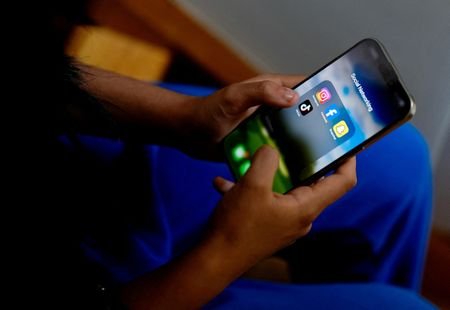 High school student poses with her mobile showing her social