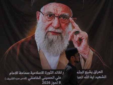A man walks past a banner bearing a portrait of