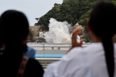 People watch waves crash against the shore as Typhoon Bavi