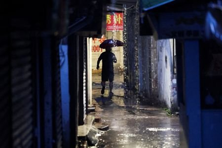 A person walks with an umbrella as Typhoon Bavi approches
