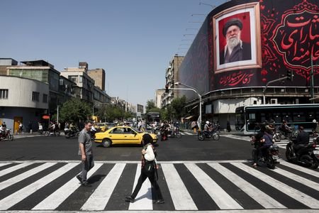 People walk past a billboard with an image of Iran's