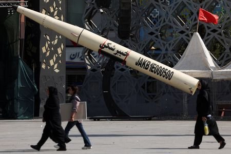 People walk next to a symbolic mockup of an Iranian