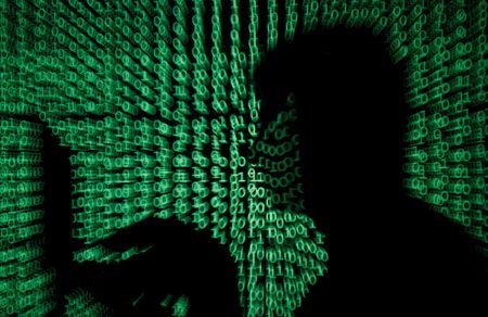FILE PHOTO: Man holds laptop computer as cyber code is