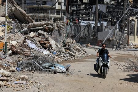 A man rides past the rubble of buildings damaged in