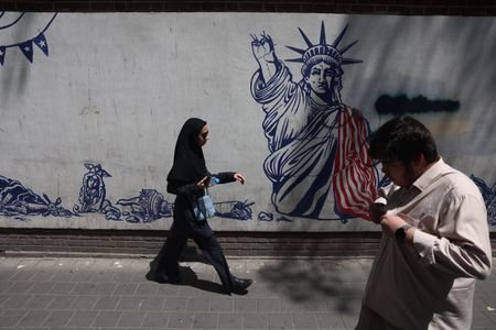 People walk near an anti-U.S. mural in Tehran