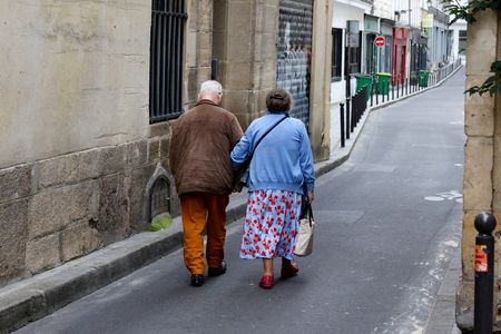 FILE PHOTO: Two older people walk arm-in-arm down a side