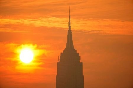 The sun rises next to The Empire State Building through