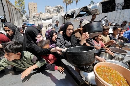 Palestinians gather to receive food from a charity kitchen, in