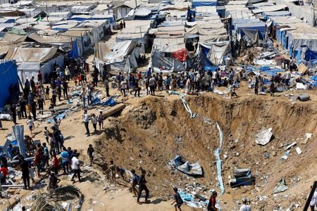 Palestinians inspect the site of an overnight Israeli strike on