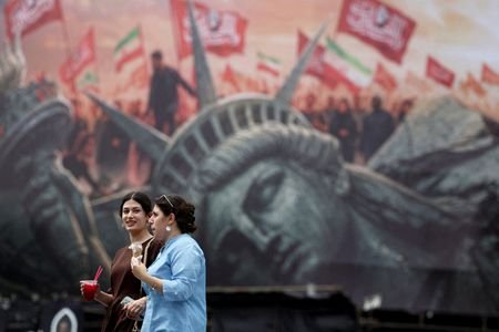 People walk past an anti-U.S. billboard on a street in