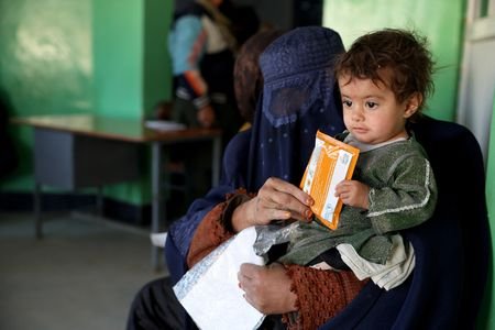 Halima, 40, holds her child with a sachet of Plumpy’Nut,