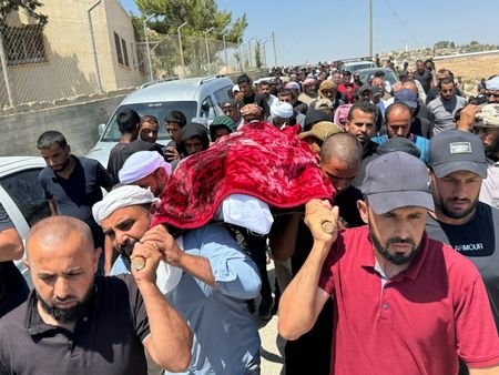 Mourners hold prayers next to the body of well-known Palestinian