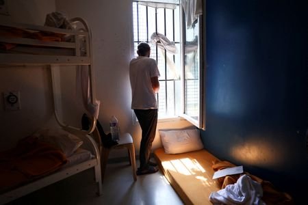 An inmate looks out the window from his prison cell