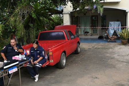 Emergency personnel sit outside the house where a Thai teenager