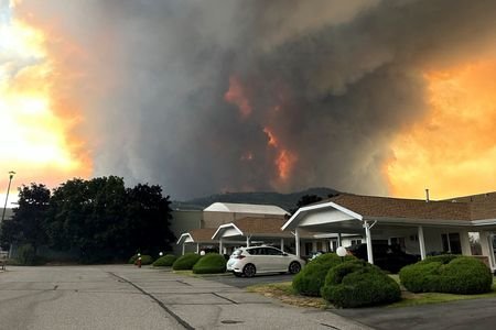 Smoke rises from the Bald Range wildfire over a residential
